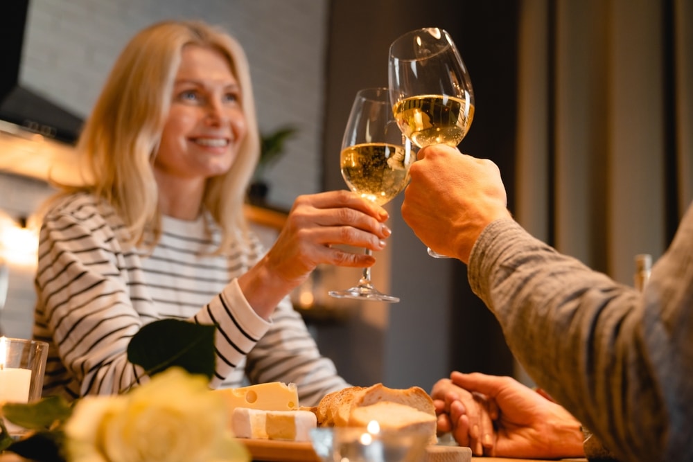 Couple clinking white wine glasses and enjoying a meal at one of the top St. Augustine restaurants
